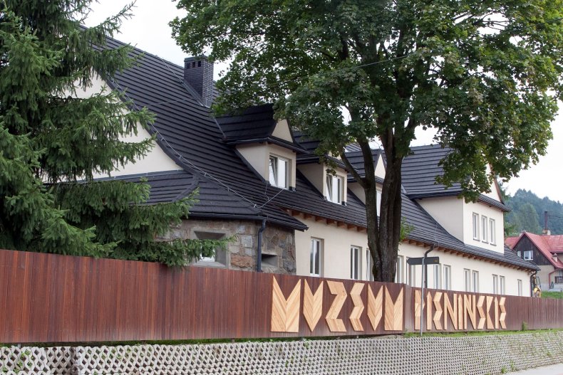 A large building behind the fence with the inscription MUZEUM PEININŚKIE