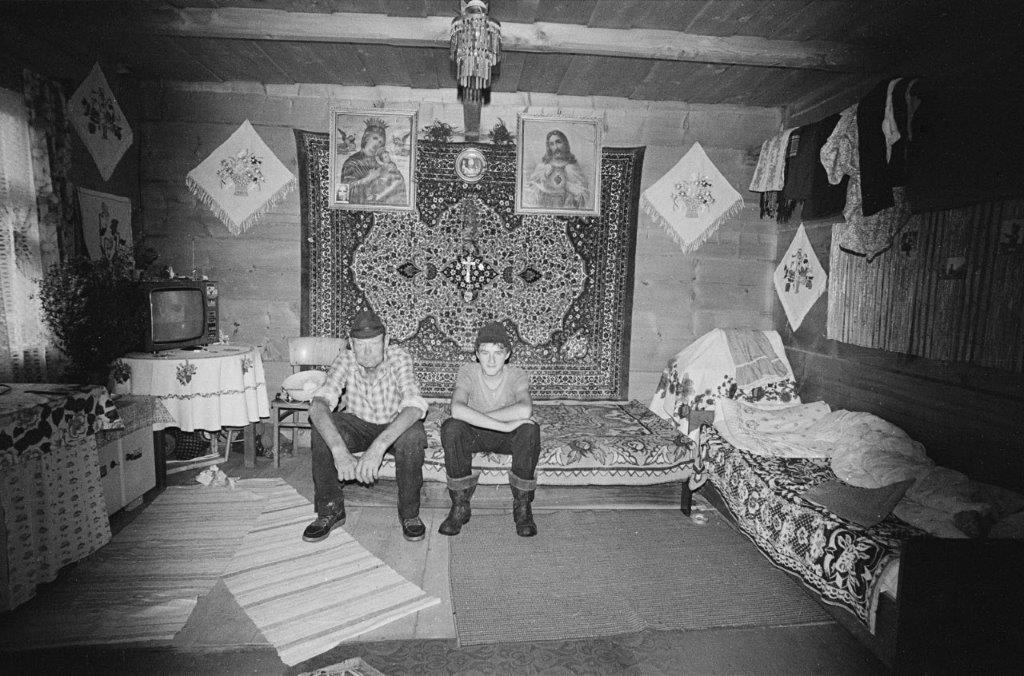 Dwóch mężczyzn siedzących na tapczanie w izbie