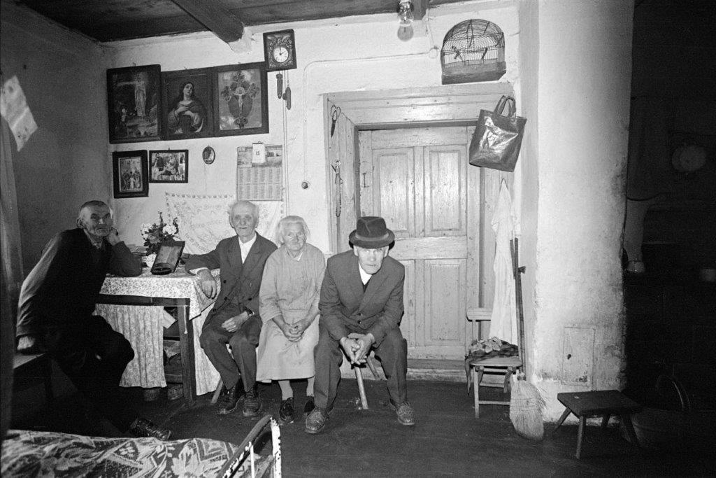 Trzech starszych mężczyzn i kobieta w izbie wiejskiego domu