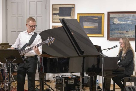 25.	Dwóch mężczyzn, jeden gra na gitarze, drugi na fortepianie.