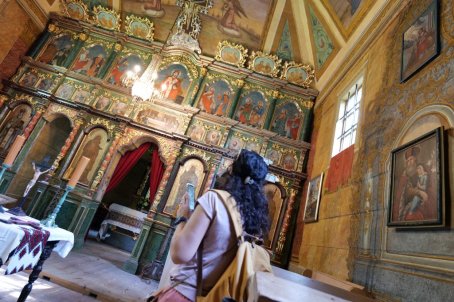 Kobieta przygląda się ikonostasowi w cerkwi