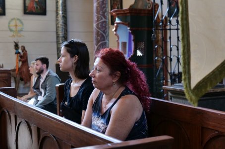 Kilka osób słucha koncertu w kościele