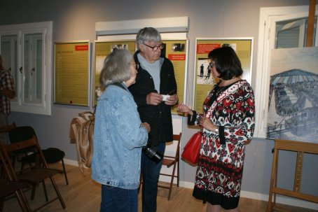 Kobieta rozmawia z dwójką ludzi, w tle wystawa.