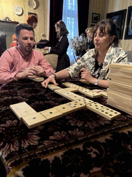 Kobieta i mężczyzna układają domino, w tle ludzie.