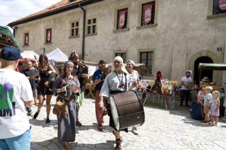 Muzykanci prowadzą korowód osób w strojach średniowiecznych