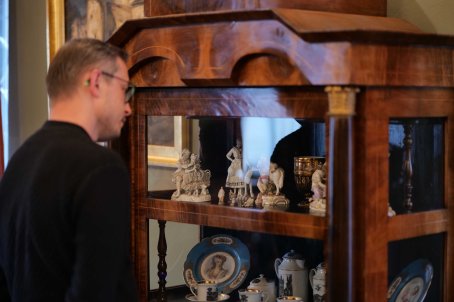 Mężczyzna przygląda się figurkom z porcelany.