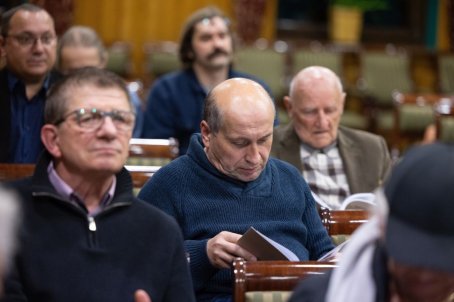 parę osób na krzesłach, jedna czyta książkę