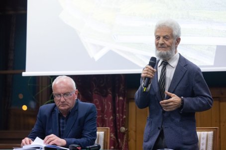 mężczyzna mówi do mikrofonu, drugi siedzi obok