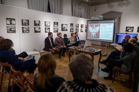 Na sali siedzą zebrani i oglądają prezentację wideo