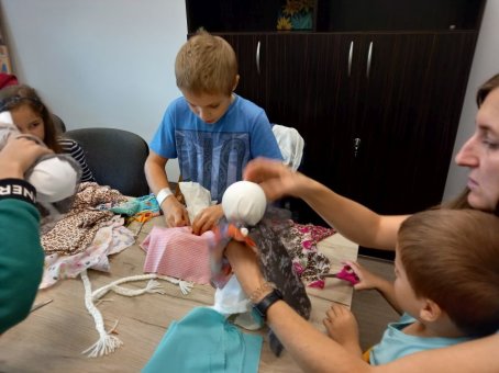 Dzieci i rodzice robią lalki z gałganków