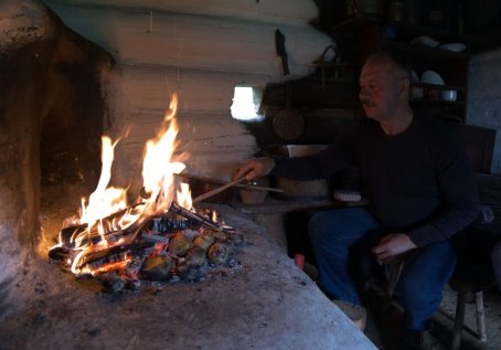 Mężczyzna rozgarnia ogień  na piecu