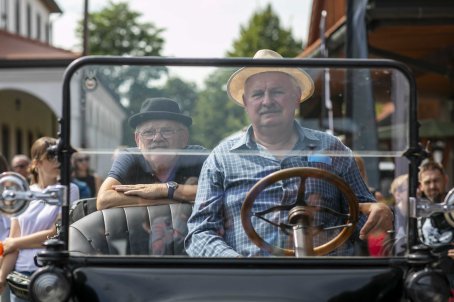 28.	Dwóch mężczyzn w pojeździe, w tle ludzie.
