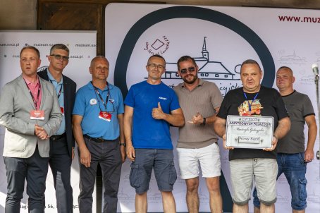 47.	Siedmiu mężczyzn na scenie, jeden z nich trzyma tablicę