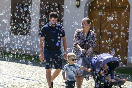 36.	Mężczyzna i kobieta idą z dziećmi, wokół nich bańki mydlane