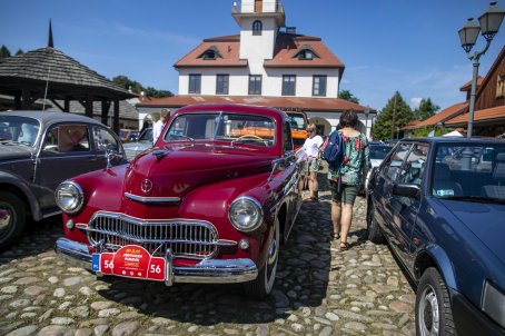 34.	Ludzie oglądają samochody, w tle budynki